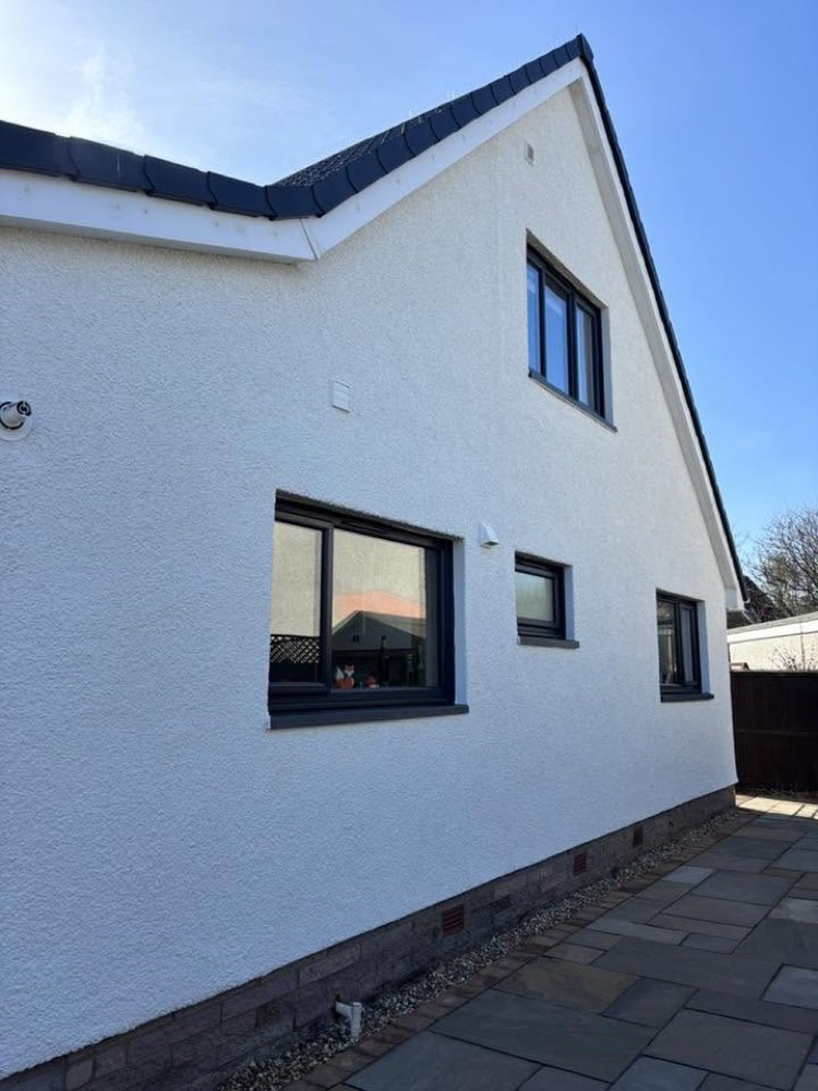 A freshly coated white render wall with modern grey windows